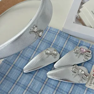 Silver bow hairband and clip set with pink heart crystals on a blue plaid background