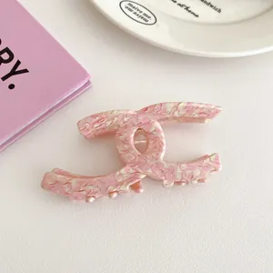Close-up of pink marble textured acetate hair claw clip with interlocking C design