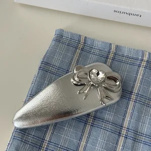 Silver bow snap hair clip with heart crystal on blue checkered fabric background