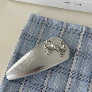 Close-up of a silver BB hair clip featuring a bow and sparkling heart-shaped crystals