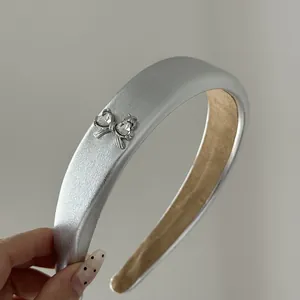 Detail of silver metallic headband with rhinestone bow and non-slip flocked lining