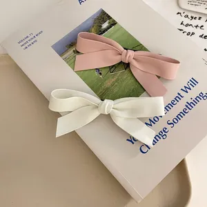 Détail de barrettes à nœuds faites main en rose et crème avec texture mate