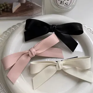 Barrettes à cheveux nœud en cuir faites main en noir, rose et beige sur une assiette