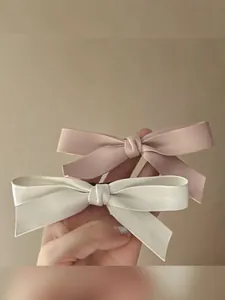Vue détaillée de pinces à cheveux à double nœud faites main en beige et rose pastel