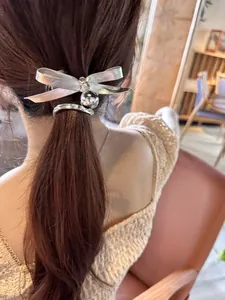 Detail van een matte zilveren metalen haarclip met strik en gepolijste bolvormige hanger