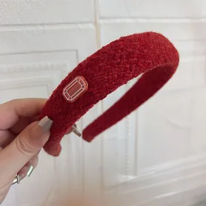 Close-up of deep red tweed headband with thick woven texture and rectangular detail