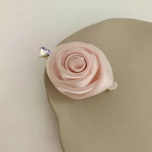 Détail de pince à cheveux rose satinée avec fermoir doré et strass en forme de cœur