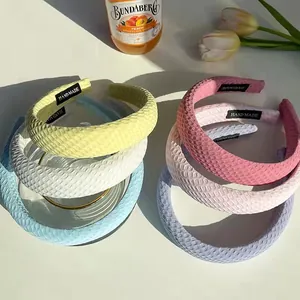 Detail of grid patterned wide headbands with HAND MADE labels in soft pastel tones