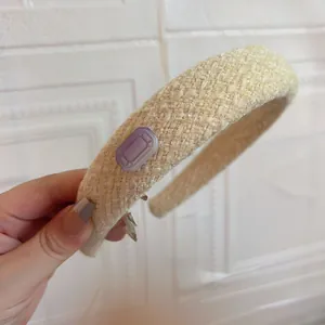 Detail of beige woven headband with sparkling purple octagonal gemstone decoration