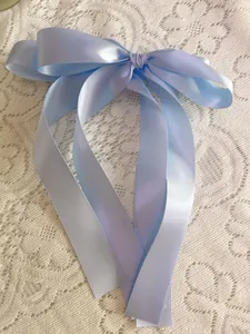 Detail of light blue satin ribbon bow with elegant long streamers on white lace fabric