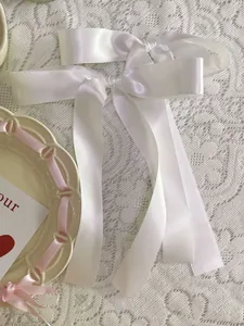 Detailed view of white satin ribbon hair bows with elegant long tails on lace background