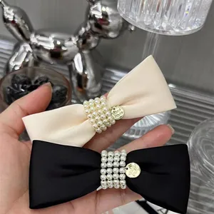 Elegant satin bow hair clip set with pearls and gold tags in black and cream white