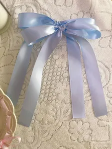 Close-up of light blue satin ribbon bow with long streamers on lace fabric