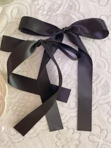 Detail of elegant black satin ribbon bows with long streamers on white lace fabric