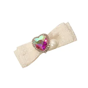 Barrette nœud crème avec pierre en forme de cœur irisé et détail de perle délicate