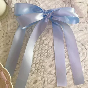 Elegant light blue satin ribbon bow with long streamers on a white lace background