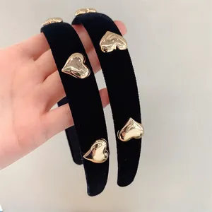 Close-up of black velvet headbands featuring polished gold heart-shaped metal accents