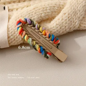 Close-up of a 6.8cm colorful woven wool hair clip on a soft beige knit background