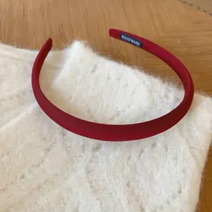 Elegante cerchietto rosso opaco fatto a mano su peluche bianco e superficie di legno