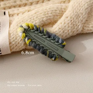 Detail shot of a 6.8cm handmade knit hair clip with olive green metal and colorful yarn