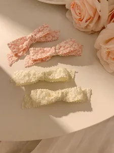Detailed macro view of four pink and cream floral bow hair clips with jacquard texture