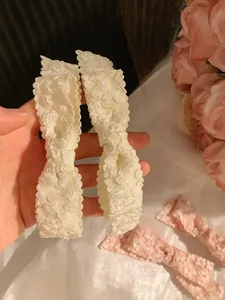 Detail of pink and beige floral bow hair clips featuring 3D embossed jacquard fabric texture