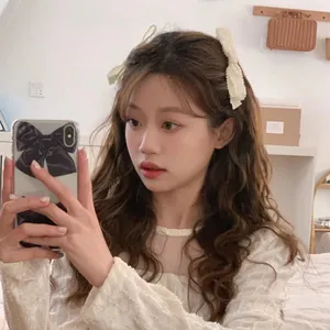 Detail of cream pleated bow hair clip and black bow phone case in a sweet Korean style