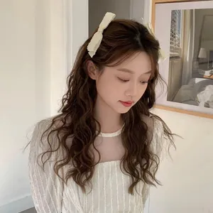 Close-up of cream-white pleated bow hair clips worn by a model in a feminine style