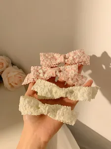 Detailed texture of pink and cream bow hair clips with soft bubble fabric and lace finish