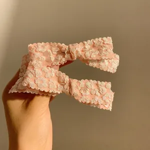 Close-up of pink bow hair clips with floral texture and scalloped edges for women