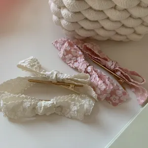 Elegant floral lace bow hair clips in pink and white with gold alligator metal grip