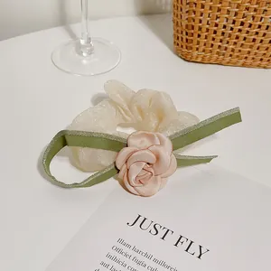 Elegant off-white camellia hair scrunchie with pink floral detail and green ribbons