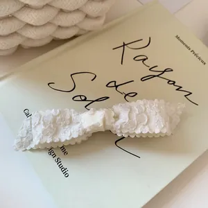 Detail of white jacquard floral bow hair clip on a vintage book for an elegant style