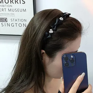 Elegante cerchietto in raso nero con fiocchi e cristalli a cuore su una modella