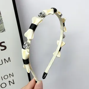 Dettaglio del cerchietto crema con fiocchi neri e strass a forma di cuore lucidi