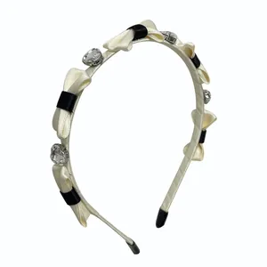 Elegante cerchietto con fiocchi crema e neri e cristalli a forma di cuore