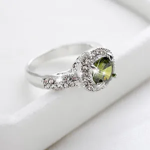 Detalle del anillo de circón verde oliva con halo brillante y banda de plata fina