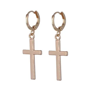 Detailed close-up of golden huggie hoop earrings featuring smooth cross-shaped pendants