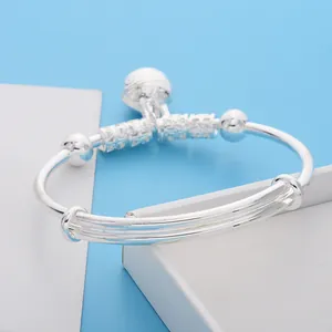 Close-up of silver baby bell bangle with adjustable slide and hollow carved beads