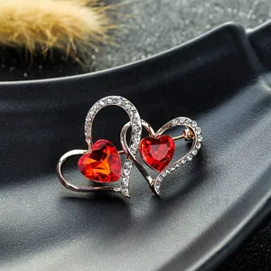 Vista macro del broche de doble corazón con gemas rojas y circonitas blancas brillantes