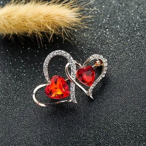 Detalle del broche de corazones entrelazados con cristales rojos y pedrería blanca