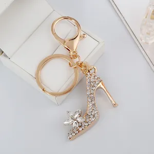 Llavero elegante de zapato de tacón dorado con cristales sobre una caja