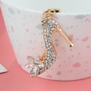 Colgante de zapato dorado con flor de cristal y pedrería brillante sobre una taza