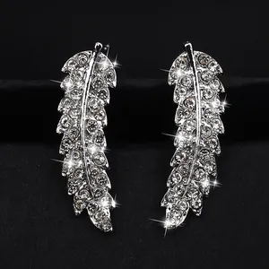 Macro shot of silver feather earrings with sparkling rhinestones on black velvet