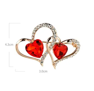 Vista de detalle del broche de doble corazón con gemas rojas y pedrería de cristal