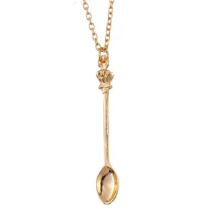 Macro shot of a vintage gold crown spoon pendant with a delicate link chain necklace