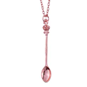 Macro detail of rose gold crown spoon pendant with delicate metal cross chain
