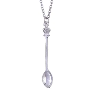 Detailed view of crown-topped silver spoon pendant on a metallic chain necklace