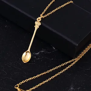 Close-up of golden crown spoon pendant necklace on a dark marble jewelry box background