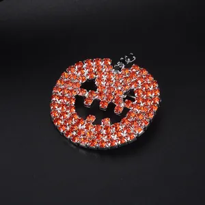 Macro detail of pumpkin brooch featuring orange rhinestones and Jack-o'-lantern smile